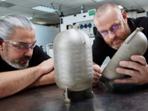 Engineers examine a titanium fuel tank printed on a VELO3D additive manufacturing system with no internal supports. 