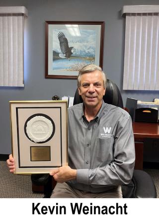 Kevin Weinacht, company founder, holds to the Eriez Merlin award.