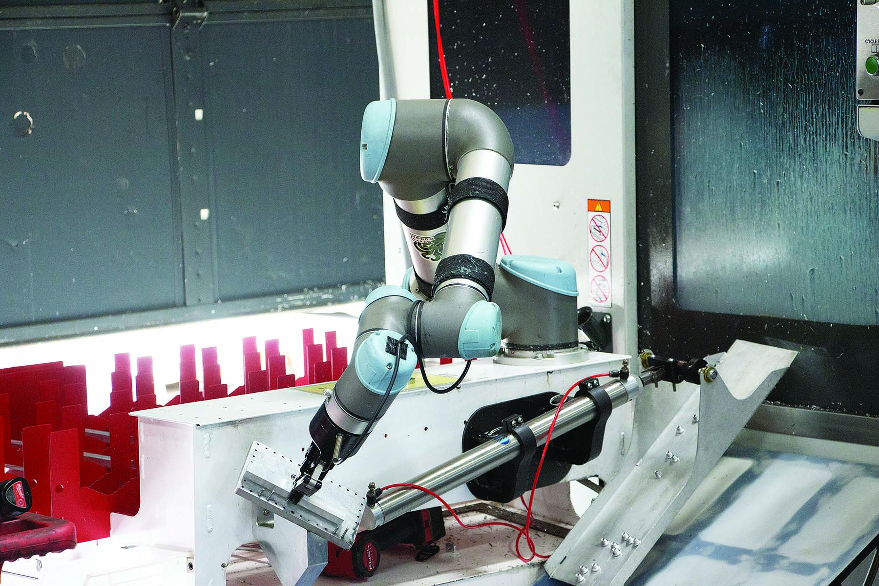 For each part machined at Go Fast Campers, a cobot equipped with a force feedback gripper from Robotiq picks an aluminum workpiece from a tray, sets the workpiece in a re-grip station to find the part's center and loads it into the machine.